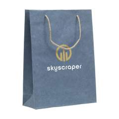 WoW! Stabile Papiergeschenktasche (Größe L) aus Recyclingpapier mit Jeansfasern (180 g/m²). Durch die Verwendung von recycelten Jeansstoffen kann die Farbe Blau von Tasche zu Tasche variieren. Die blaue Farbe verleiht der Tasche einen trendigen Look. Die Tasche hat zwei kurze Jute-Trageschlaufen, einen gefalteten Boden und eine Seitenfalte. Geeignet für alle Arten von Werbezwecken. Für die Herstellung dieser Tasche werden keine Bäume gefällt.