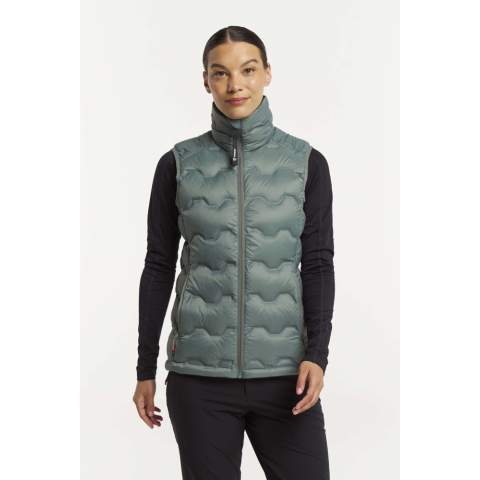 Deze lichtgewicht, RDS-gecertificeerde donsbodywarmer (90/10 dons/veren 650 vulkracht) is wind- en waterafstotend, waardoor hij het hele jaar door ideaal is voor elke buitenactiviteit. Het Shibui Down Vest kan als buitenlaag of onder een shelljack worden gedragen voor extra warmte – het past als gegoten bij ons ultramoderne Shibui skishelljack! De bodywarmer is gemaakt van 100% gerecycled polyesterweefsel en heeft gelijmde kanalen gevuld met verantwoord geproduceerd, volledig traceerbaar, RDS-gecertificeerd dons. Hij beschikt over een verstelbare zoom en twee voorzakken met ritssluiting.<br /><br />Hij wordt geleverd met een PFC-vrije waterafstotende afwerking. Het ontwerp van het TXlite Shibui Down Vest is geïnspireerd op het Japanse woord 'shibui', dat verwijst naar een ingetogen en strakke esthetiek met fijne details zoals geselecteerde materialen, texturen en uitstekende functionaliteit.