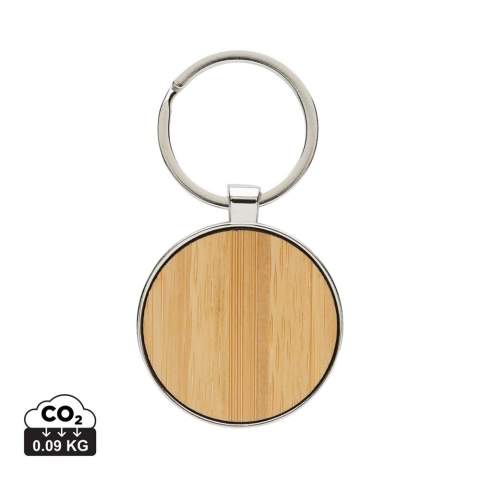Ronde sleutelhanger gemaakt van RCS-gerecycled zinc alloy en bamboe. Totaal gerecycled materiaal: 73% op basis van het totale gewicht van het item. RCS-certificering zorgt voor een volledig gecertificeerde toeleveringsketen van de gerecyclede materialen. Verpakt in papieren zak