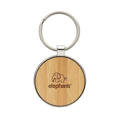 Ronde sleutelhanger gemaakt van RCS-gerecycled zinc alloy en bamboe. Totaal gerecycled materiaal: 73% op basis van het totale gewicht van het item. RCS-certificering zorgt voor een volledig gecertificeerde toeleveringsketen van de gerecyclede materialen. Verpakt in papieren zak