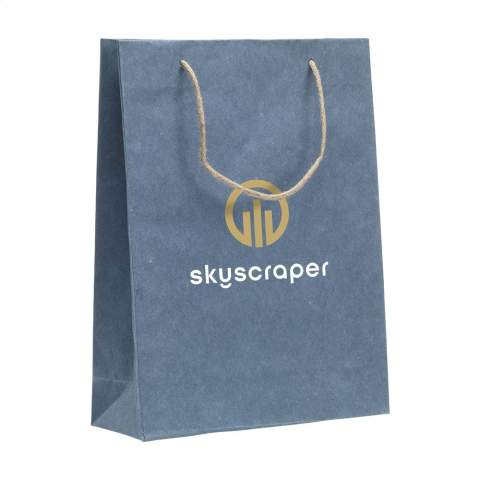 WoW! Sac cadeau robuste (taille L) en papier recyclé avec fibres de jeans (180 g/m²). En raison de l'utilisation de tissus de jeans recyclés, la nuance de bleu peut différer d'un sac à l'autre. La couleur bleue donne au sac un look tendance. Le sac est doté de deux poignées de transport courtes en jute, d'un fond plié et d'un pli latéral. Convient à toutes sortes de fins promotionnelles. Aucun arbre n'a été abattu pour la production de ce sac.