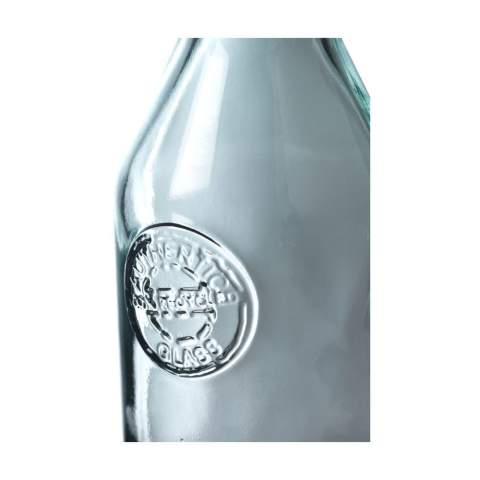 WoW! Decorative water bottle with spout. Made from 100% recycled, robust quality glass. Closes with a cork cap. An attractive bottle with character. The glass is embossed with the 'Authentic Glass 100% recycled' label.     The blue-green tint of this glass is a natural result of the recycling process. The colour and any imperfections emphasise the beauty of this recycled product and contributes to its authenticity. Recycling reduces the consumption of new raw materials, water and energy. Colour, thickness and size may vary by product. Made in Spain. Capacity 1,200 ml.