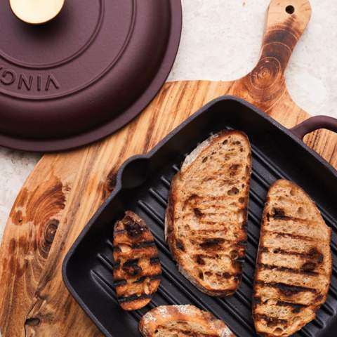 A classic enamelled cast iron grill pan with a griddle that elevates the contents and produces indirect heat, akin to a grill. This design also allows for efficient drainage of fat, preventing the food from cooking in excess fat. The cast iron material ensures even distribution of heat throughout the griddle and enables it to retain heat for a prolonged period. The pan's durability enables it to be used on various heat sources, including the oven, making it ideal for keeping dinner warm for extended periods.
