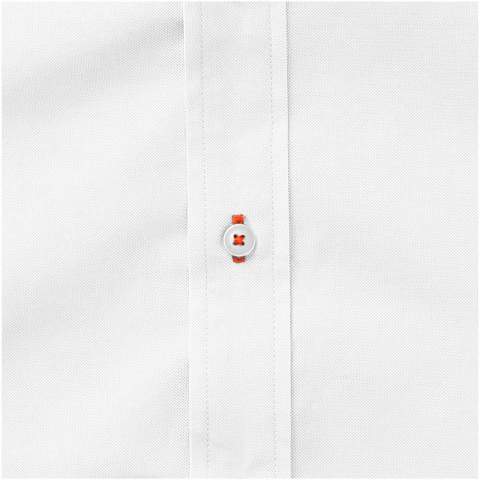 Das langärmelige Vaillant Oxford-Hemd für Damen - ein zeitloser Stil mit außergewöhnlicher Qualität. Das klassische Oxford-Gewebe aus hochwertiger Baumwolle verleiht dem Hemd eine raffinierte Textur, die dem Gesamtbild Tiefe und Charakter verleiht. Mit seinem Button-Down-Kragen lässt es sich mühelos von formellen zu legeren Anlässen kombinieren. Das zweite Knopfloch von unten ist mit einer auffälligen orangefarbenen Naht verziert, die einen Hauch von Eleganz verleiht. Dieses Hemd hat eine taillierte Form für einen femininen Look.