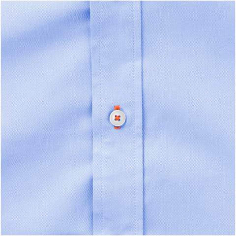 Het Vaillant oxford overhemd voor dames met lange mouwen - een tijdloze stijl van uitzonderlijke kwaliteit. Gemaakt van katoen van hoge kwaliteit, geeft het klassieke oxfordbinding het overhemd een verfijnde textuur die diepte en karakter toevoegt aan de algehele uitstraling. Met zijn button-down kraag gaat het moeiteloos over van formele naar casual gelegenheden. Het tweede knoopsgat vanaf de onderkant is versierd met opvallende oranje stiksels en voegt een vleugje elegantie toe. Dit overhemd is ontworpen met een getailleerde vorm voor een vrouwelijke look.