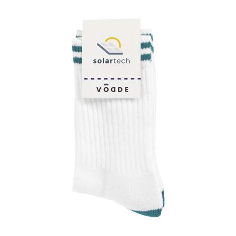 Bequeme, 100% zirkuläre Socken der Marke Vodde. Die Socken bestehen zu 53% aus recycelter Baumwolle (gesammelte Stofflappen), zu 38% aus recyceltem Polyester (aus gesammelten PET-Flaschen), 6% aus Nylon und zu 3% aus Elasthan. Inklusive eingestricktem, individuellem Design. Die Socken sind standardmäßig mit einem Etikett aneinander befestigt, das in Ihrem eigenen, vollfarbigen Design bedruckt werden kann. So entwerfen Sie Ihre eigenen Socken, die perfekt zu Ihrem Corporate Design und Ihren Wünschen passen. Diese Qualitätssocken haben eine verstärkte Sohle und sind ideal, um sie beim Sport oder bei Wanderungen zu tragen.   • Erhältlich in den Größen M (36-40) und L (41-46). • Mindestbestellmenge: 100 Paar Socken pro Größe. Mindestbestellmenge insgesamt: 200 Paar Socken.  • Optional: Lieferung paarweise in einer (individuell gestalteten) Schachtel aus recyceltem Karton - ab 1.200 Paar Socken möglich.   • Wenn Sie diese umweltfreundlichen Socken tragen, leisten Sie einen Beitrag zu einer nachhaltigen Welt mit weniger Umweltverschmutzung. Entwickelt und getestet in den Niederlanden. Made in the EU.  •  Das niederländische Unternehmen Vodde recycelt ausrangierte Textilien und stellt daraus neue Produkte her, die von niederländischen Designern entworfen werden. Vodde stellt seine Garne aus Baumwolle her, die von lokalen „Lumpenhändlern“ gesammelt wird, sowie aus Abfällen von Textilproduktionen in europäischen Ländern, in denen Vodde seine eigenen Produkte herstellt. Darüber hinaus werden Polyester aus PET-Flaschen, Nylon, Fischernetzen und anderen gesammelten Abfällen verwendet.