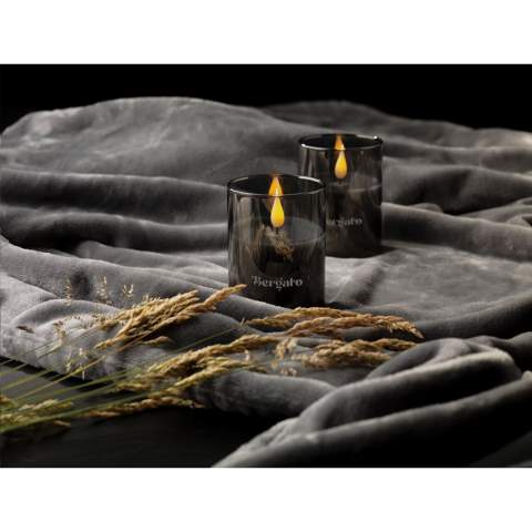 LED candle in a chic smoke glass from the Wooosh brand. Complete with a warm and atmospheric LED light and real wax finish for an authentic look & feel. This candle is a safe way to create atmospheric lighting without the risk of fire, producing the same warm effect as a traditional candle.  Ideal for indoor and outdoor use, this LED candle is also perfect for creating a cosy atmosphere when dining or during special occasions. Includes 2 batteries. Each item is supplied in a luxurious Wooosh gift box.