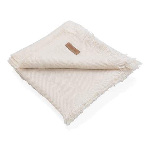 Couverture 130x150cm Ukiyo Aware™ Polylana® tissée avec des bords frangés. Gardez-la sur votre canapé pour des soirées cinéma douillettes ou sur votre lit pour un beau look. Avec le traceur AWARE™ qui valide l'utilisation authentique de matériaux recyclés. 2 % du produit de la vente de chaque produit contenant AWARE™ sera reversé à Water.org.