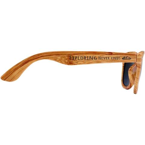 Zonnebril met retrodesign en afwerking in houtlook. Deze zonnebril met UV 400-lenzen is geclassificeerd als categorie 3, waardoor ze de perfecte keuze zijn voor bescherming tegen fel zonlicht. Voldoet aan EU-veiligheidsnorm EN12312-1. Het PC plastic zorgt ervoor dat het product licht buigbaar is voor comfort.