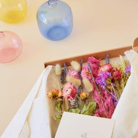 Deze droogbloemen die door de brievenbus passen, bieden een bijzonder en duurzaam geschenk. Droogbloemen voegen een vleugje natuurlijke schoonheid toe aan elke ruimte. Ze blijven lang mooi en hebben geen speciale verzorging nodig, wat het perfect maakt voor zowel thuis als op kantoor. Door hun natuurlijke uitstraling brengen ze een ontspannen sfeer met zich mee, wat helpt om stress te verminderen en de creativiteit te stimuleren. Een perfect artikel om mee te stralen op het bureau bij jouw relatie.<br /><br />Dit droogbloemen setje is volledig aanpasbaar in zowel kleur als met de toevoeging van een logo of slogan. De buisjes kunnen worden gevuld met gekleurde droogbloemen die passen bij de huisstijl van jouw bedrijf. Naast de bijzondere optie om de droogbloemen in kleur te personaliseren, biedt de houten standaard ook ruimte voor een logo of slogan. Hierdoor wordt de herkenning van jouw merk versterkt en wordt waardering voor de relatie getoond.<br /><br />Heeft u vragen over dit product, de gewenste personalisatie of eventuele verpakkingen? Neem dan gerust contact met ons op.